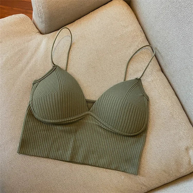 The Womens Sexy Halter Crop Top in olive green features a ribbed design, V-neckline, defined cups, and thin straps. Made from breathable nylon, its styled on a beige cushioned sofa for a chic European-inspired look.