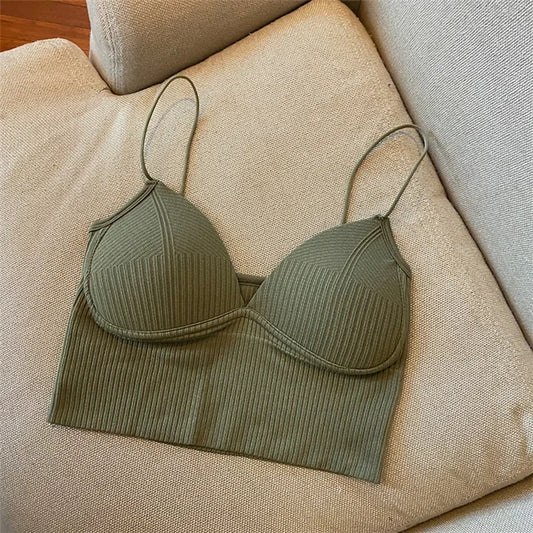 The Womens Sexy Halter Crop Top in olive green features a ribbed design, V-neckline, defined cups, and thin straps. Made from breathable nylon, its styled on a beige cushioned sofa for a chic European-inspired look.