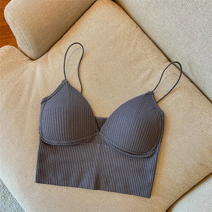 The Womens Sexy Halter Crop Top, featuring ribbed fabric and European styling in dark gray, with thin straps, is displayed flat on a light beige upholstered sofa.