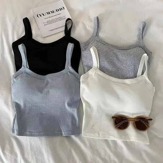 Four Crop Top Women Sexy Sleeveless Tops in black, gray, light blue, and white are displayed on a white surface, with brown sunglasses and a sheet of paper placed nearby—ideal for summer style.