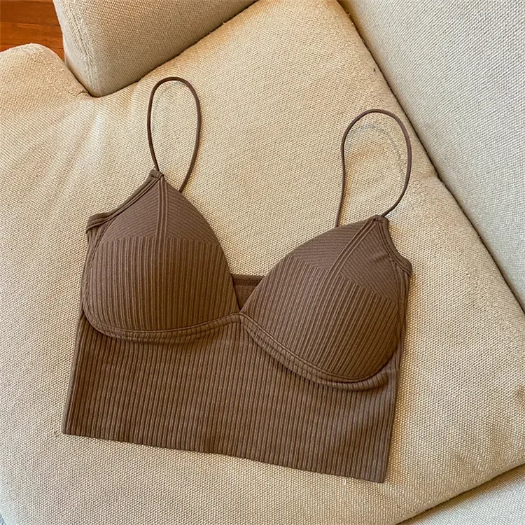 A Womens Sexy Halter Crop Top in brown with thin straps and ribbed texture, inspired by European style, is laid flat on a beige cushioned sofa.